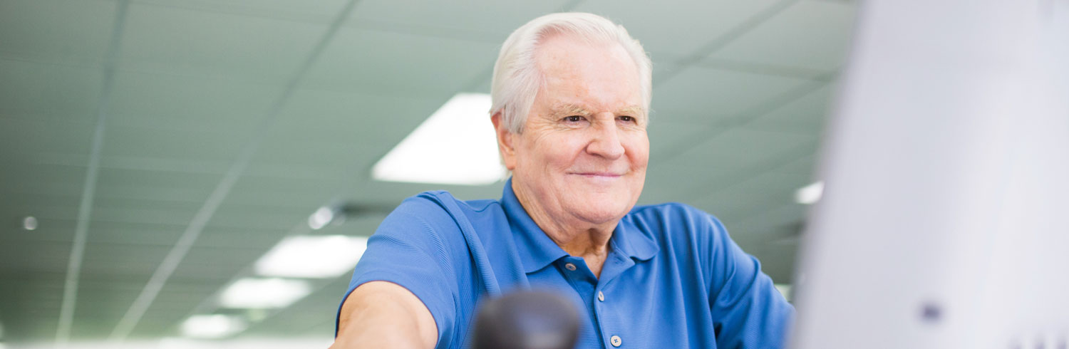 Senior man exercising with a smile in a gym.