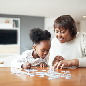 Shot of a little girl building a puzzle with her grandmother at home