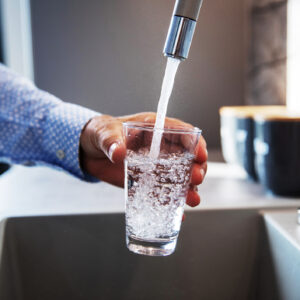 Mature male hand pouring a glass of water from tap in the kitchen sink