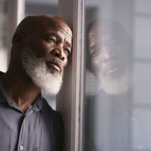 Sad, depression or black man burnout at window with mental health, headache or anxiety in house. Lonely, stress or depressed man thinking for financial problem, health compliance or finance policy