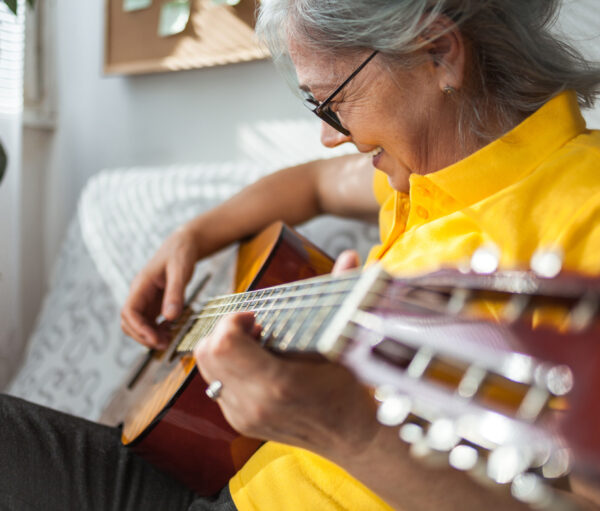 Close up of Senior woman playing guitar ay home